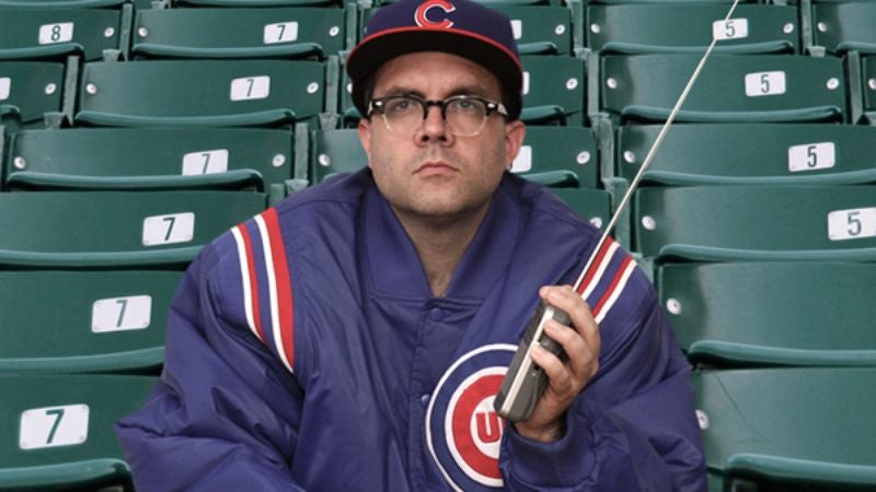 Team Jacket-Wearing, Transistor Radio-Listening Fan Sitting By Himself