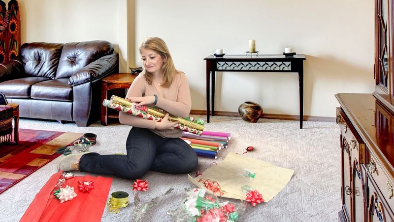 Mom Gathers Rolls Of Wrapping Paper Around Her To Stroke Softly