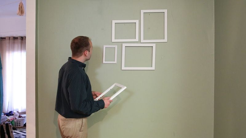 Man Not Sure Why Girlfriend Having Him Hang Cluster Of Empty Picture Frames But Willing To Go With It