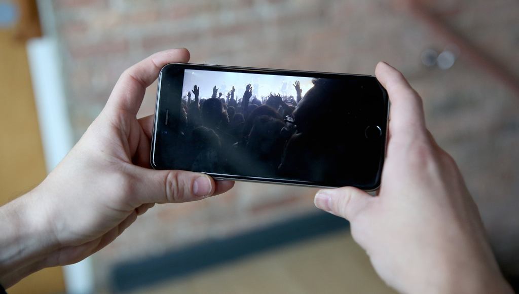 Friends Excitedly Gather Around Man’s Phone To Watch Shaky Footage Of Concert