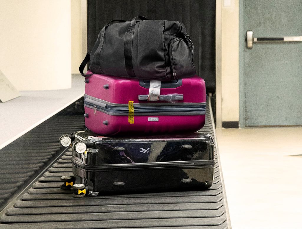 Duffel Bag Sitting Atop Two Suitcases On Luggage Carousel Like King On Opulent Throne