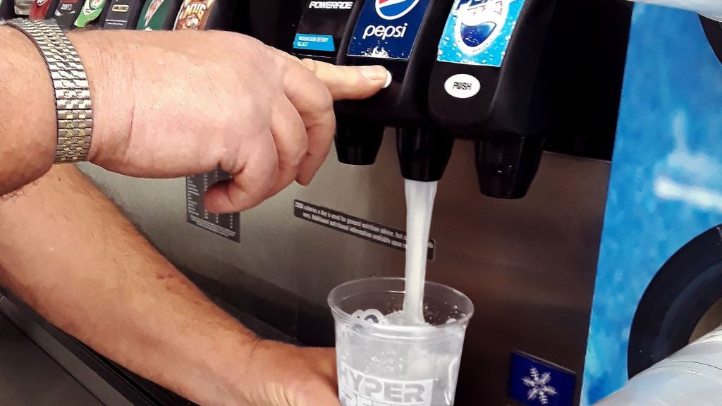 Man Looks On Helplessly As Cascade Of Clear Liquid Fills Cup At Soda Fountain