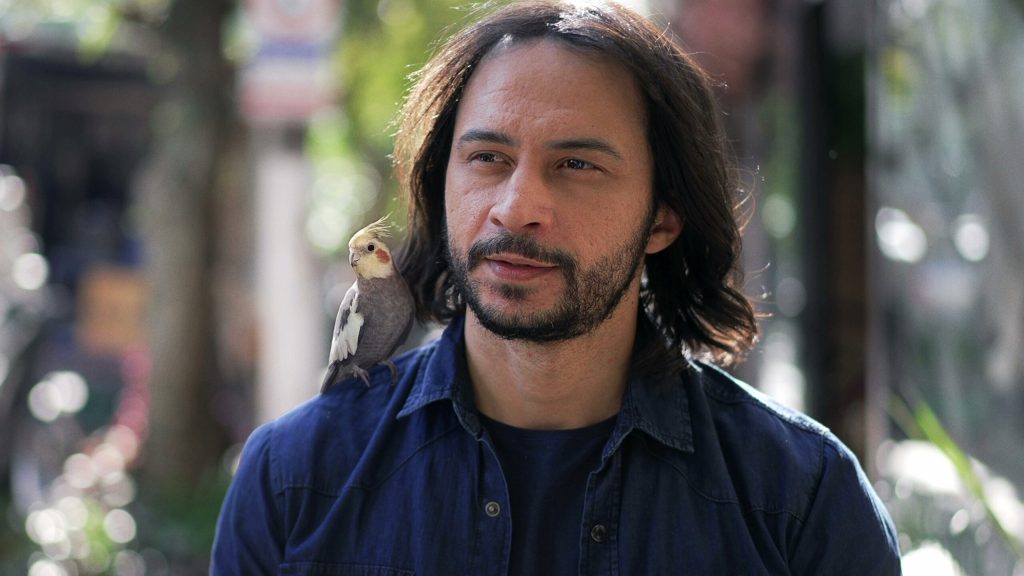 Man With Cockatiel On Shoulder Gives Knowing Nod To Man With Iguana On Shoulder